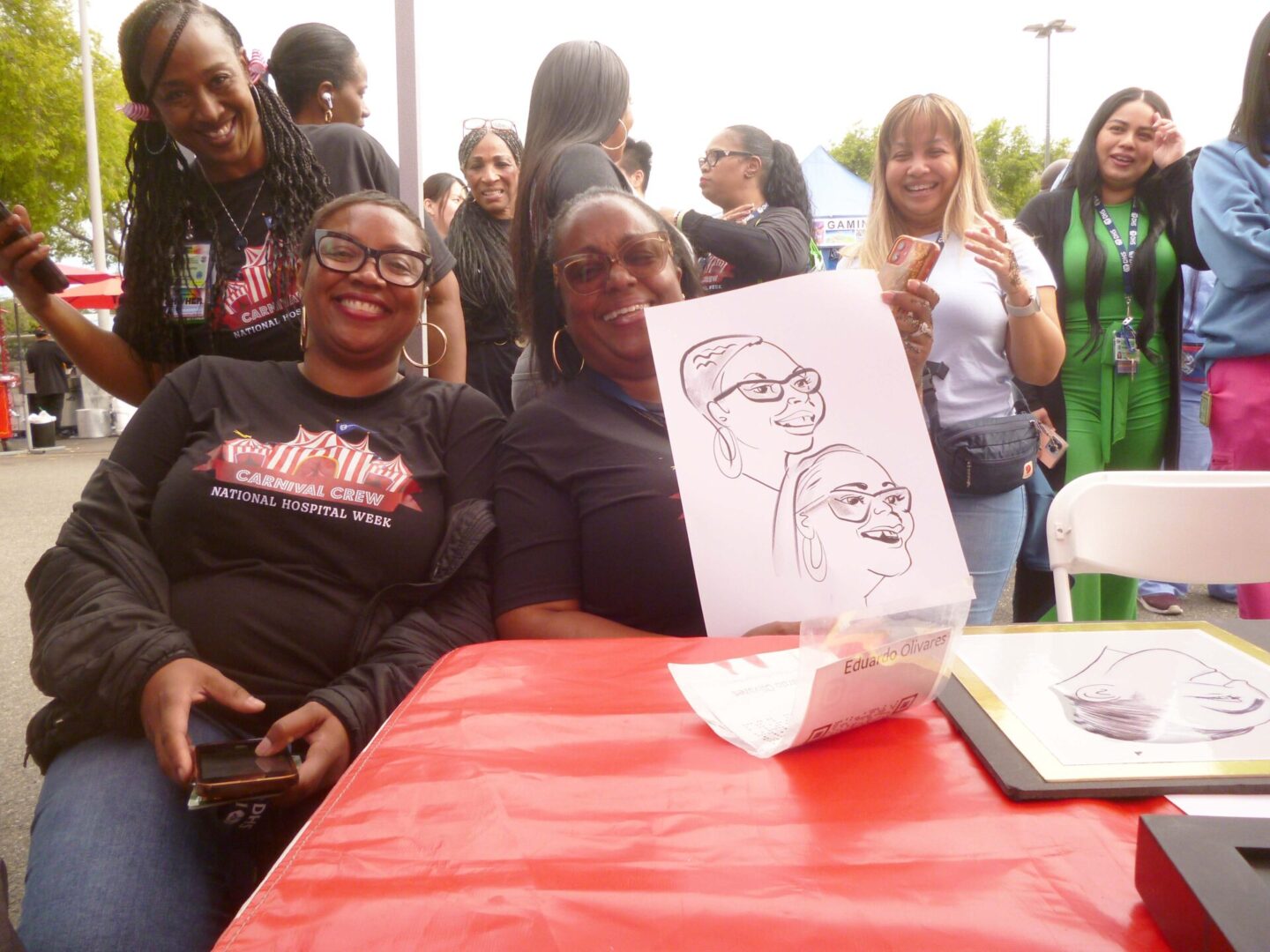 Two women with caricature drawing at event